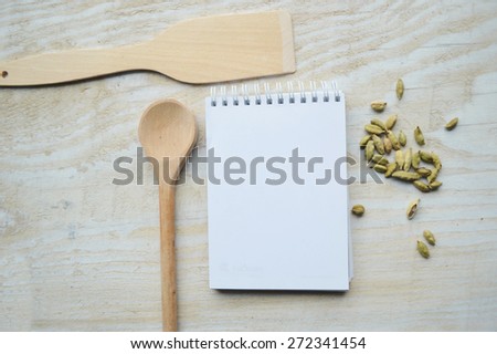 wooden spoon, notebook, recipe book, spices on a wooden table
