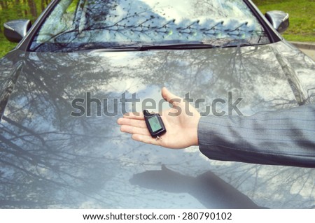 driver hand shifting the gear stick.a hand holding a car\'s remote control pointing to the door