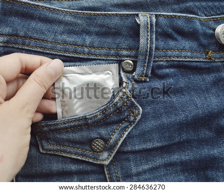 condom in blue jeans pocket,Protect yourself Use a condom.a woman holding a condom ,ready for use