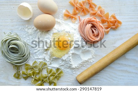 still life with raw homemade pasta and ingredients for pasta.process of cooking pasta.natural dyes for pasta (tomato, spinach, carrots),ingredients for homemade pasta(flour, eggs, water)