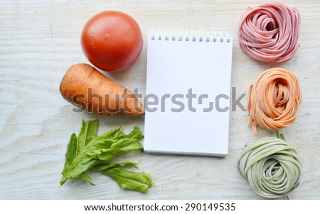 still life with raw homemade pasta and ingredients for pasta.process of cooking pasta.natural dyes for pasta (tomato, spinach, carrots),ingredients for homemade pasta(flour, eggs, water)recipe book