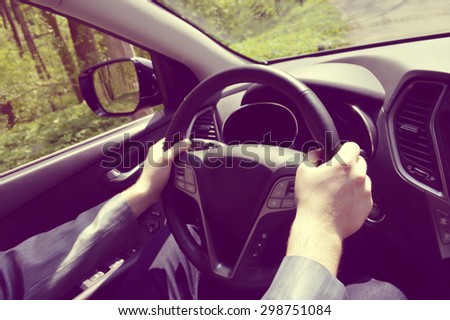 Male driver hands holding steering wheel