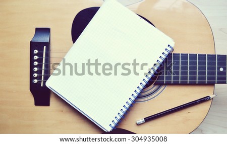 Music recording scene with classical guitar, notebook and headphones on wooden table, closeup