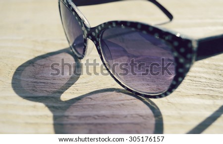 fashionable sunglasses on a wooden table closeup