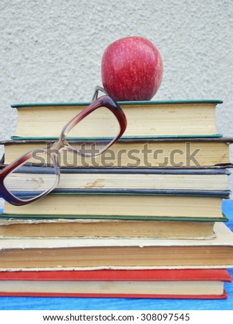 Back to school concept.autumn.Apple on old books,magnifier ,reading glasses on wooden background