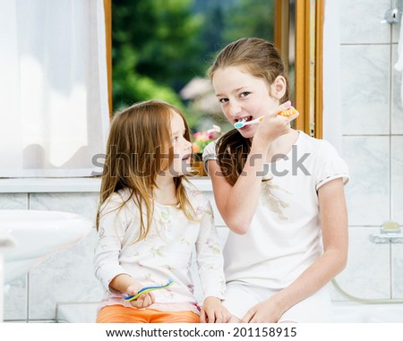 Two sisters cleaning the teeth together, morning, bathroom