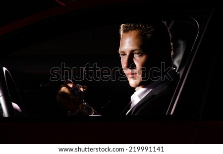 Young elegant guy sitting in luxury  modern red car