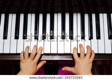 Little girl studying to play the piano at home