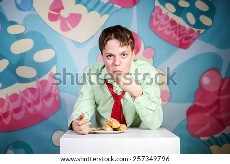 Funny teenage boy eating sweet cakes, hungry and candy man