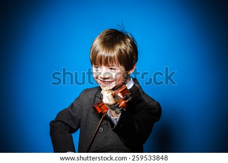 Red-haired preschooler boy with violin, isolated on blue, music concept