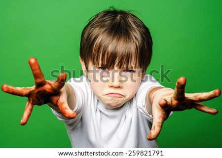 Expressive boy showing colorful hands after drawing, isolated on green
