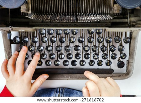 Cute little girl typing letter on vintage typewriter keyboard