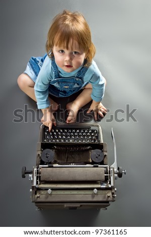 Cute little baby with retro style typewriter in studio