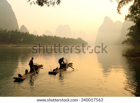 Guilin, China - October 21, 2015: Silhouette of Two Fishing Men and His Cormorants on Li River at Sunrise, Guilin, China. The Li River or Lijiang is a river in Guangxi Zhuang Autonomous Region, China.