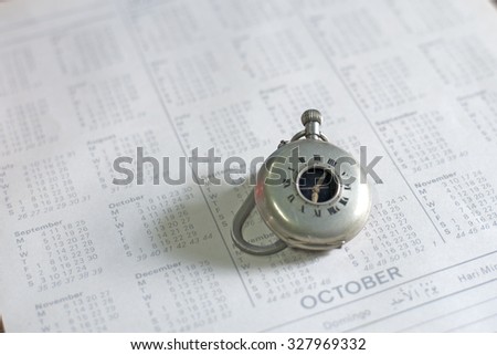 Old pocket watch on calendar page