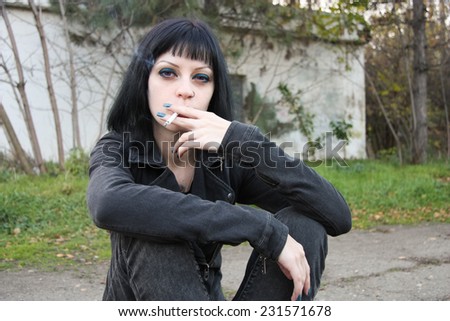 Girl smoke near rails and abandon railroad station