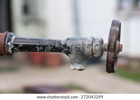 Old rusty water tap on country house