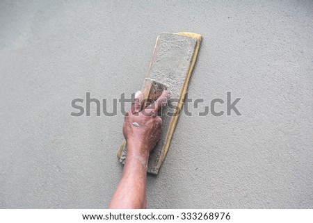 Man\'s hand plastering a wall with trowel. Construction worker. Masonry tool. Construction industry. Selective focus.