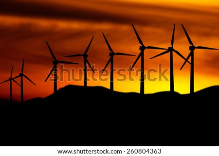 Silhouette the wind turbine over blurred sunset background