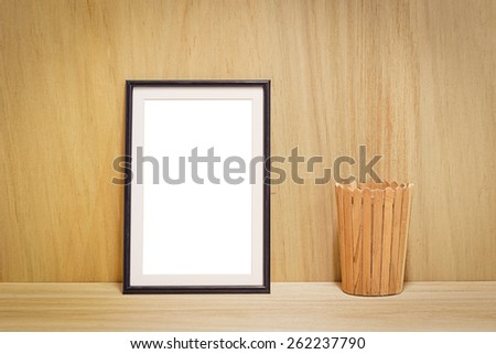 blank black picture frame and wooden bucket on the wooden background
