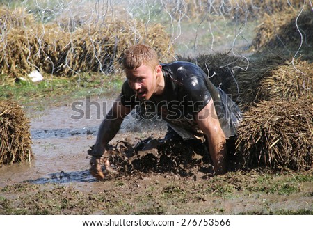 STOCKHOLM - MAY 09, 2015: Focused man falling the mud trying to avoid the hanging electrified cables during in the public obstacle race event Tough Viking, May 09, 2015 in Stockholm, Sweden
