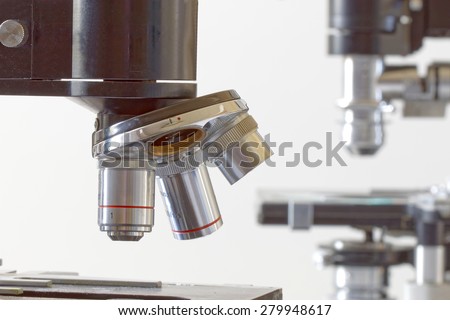Side view of two black vintage microscopes, one in focus and one de-focused in the background