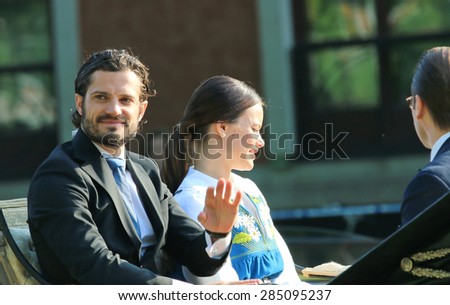 STOCKHOLM - JUN 06, 2015: Swedish prince Carl-Philip Bernadotte waiving to  audience on his way to celebrate swedish national day. Princess Sofia Hellqvist and prince Daniel Westling sitting beside