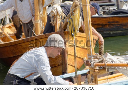 GRISSLEHAMN - JUN 13, 2015: Sailors in vintage clothes preparing old sailing ships in the public event Postrodden, June 13, 2015 in Grisslehamn, Sweden