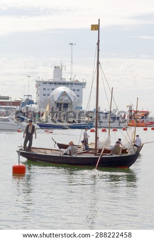 GRISSLEHAMN - JUN 13, 2015: Sailors in vintage clothes in old sailing ship in front of modern ferry in the harbor before the public event Postrodden, June 13, 2015 in Grisslehamn, Sweden