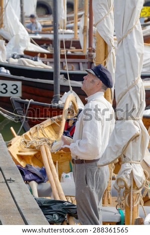 GRISSLEHAMN - JUN 13, 2015: Male sailor in vintage clothes and blue hat standing in old sailing ship in the public event Postrodden, June 13, 2015 in Grisslehamn, Sweden