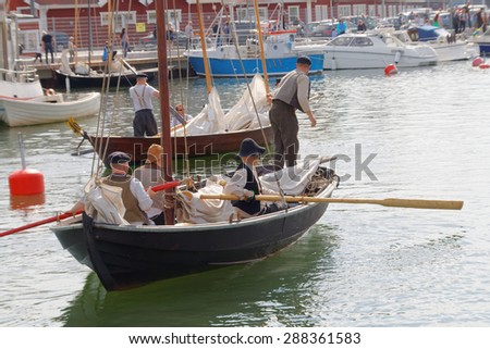 GRISSLEHAMN - JUN 13, 2015: Sailors in vintage clothes using the oars in old sailing ships in the harbor in the public event Postrodden, June 13, 2015 in Grisslehamn, Sweden
