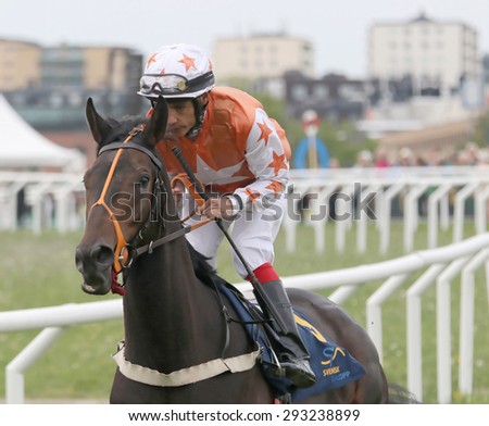 STOCKHOLM - JUNE 06: Man in orange clothes riding a race horse at the Nationaldags Galoppen at Gardet. June 6, 2015 in Stockholm