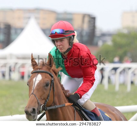 STOCKHOLM - JUNE 06: Female jockey in red, green and white clothes riding a horse race in the horse race at the Nationaldags Galoppen at Gardet. June 6, 2015 in Stockholm