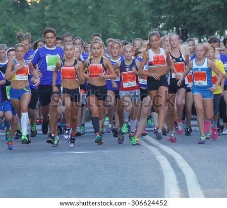 STOCKHOLM, SWEDEN - AUG 15, 2015: Group of 14 year old girls and boys running on a road during the start of the running event Midnattsloppet, August 15, 2015 in Stockholm, Sweden