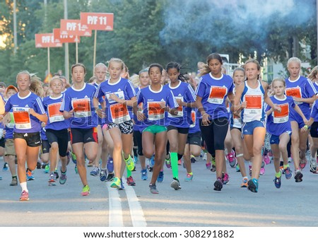 STOCKHOLM, SWEDEN - AUG 15, 2015: Group of 12 year old girls in blue dresses running in the running event Midnattsloppet, August 15, 2015 in Stockholm, Sweden
