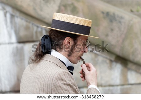 STOCKHOLM - SEPT 19, 2015: Elegant man wearing old fashioned trilby hat smoking a pipe in the Bike in Tweed event September 19, 2015 in Stockholm, Sweden