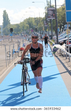 STOCKHOLM - AUG 23, 2015: Woman wearing black training bra running barefoot with bicycle in the triathlon transition zone at ITU World Triathlon event in Stockholm, 2015