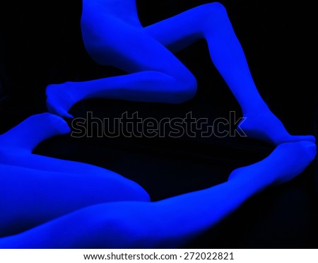 Abstract neon glowing woman legs on black background. Disco style. Techno music. Ultraviolet light with a crazy expression. Fantasy with blue fluorescent lights.