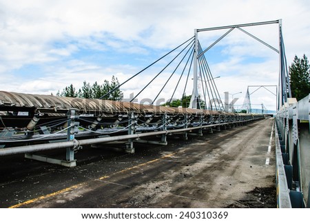 Coal was transported by coveyor belts from open-pit mine to the stock pile. Conveyor bridge was used when conveyor belts cross a road, Mae Moh mine, Lampang, Thailand.