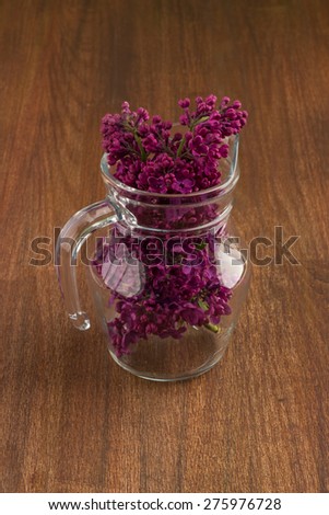 white lilac, lilac purple, white sheet of paper with hearts punching, punching with flowers on turquoise background, on a brown background, glass jug
