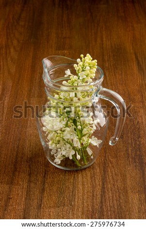 white lilac, lilac purple, white sheet of paper with hearts punching, punching with flowers on turquoise background, on a brown background, glass jug