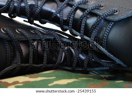 Camouflage uniform and two black leather army boots on isolated (white) background.