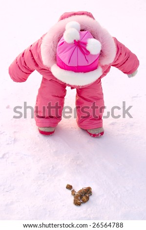 Pretty little girl in winter outerwear look all over dog\'s excrement in park.