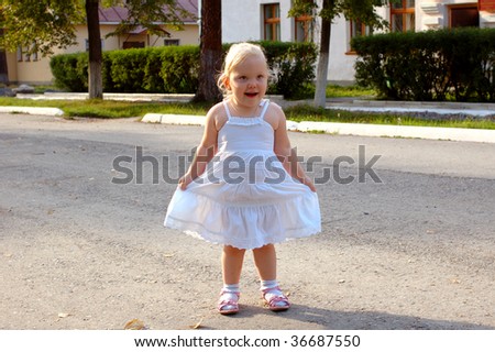 Pretty little girl in white dress walk on the road - outdoor summer portrait.