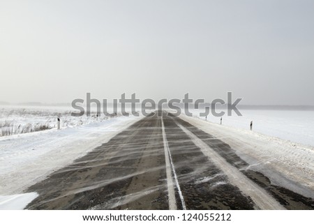 Snowing road in the middle of snow fields