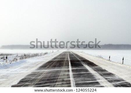 Snowing road in the middle of snow fields