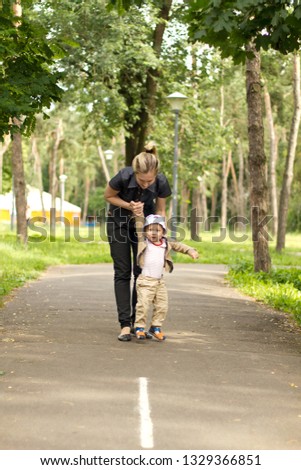 Baby Learning to Walk in Park with his Mother Behind Him. Cute Baby Boy learning to walk. First steps with mothers help