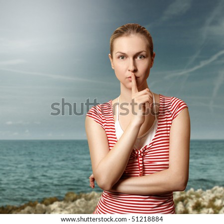 Sporty woman with finger near mouth on the beach