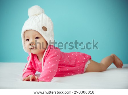 Little baby in knit winter clothing closing face with knitted beanie - Soft focus