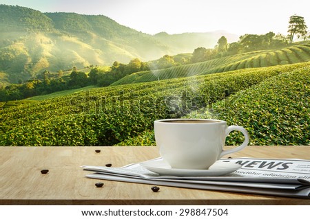 Coffee cup with newspaper on the wooden table and the Plantations background